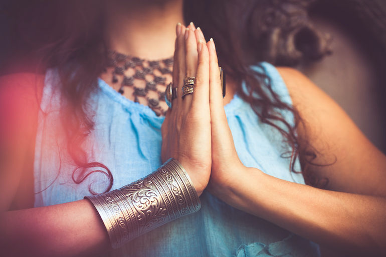 Namasté - Frau hält ihre Hände vor der Brust zusammen als Namaste Gruß