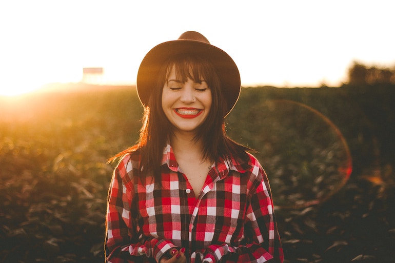 junge Frau mit Hut auf einem Feld - glücklich zufrieden dankbarkeit