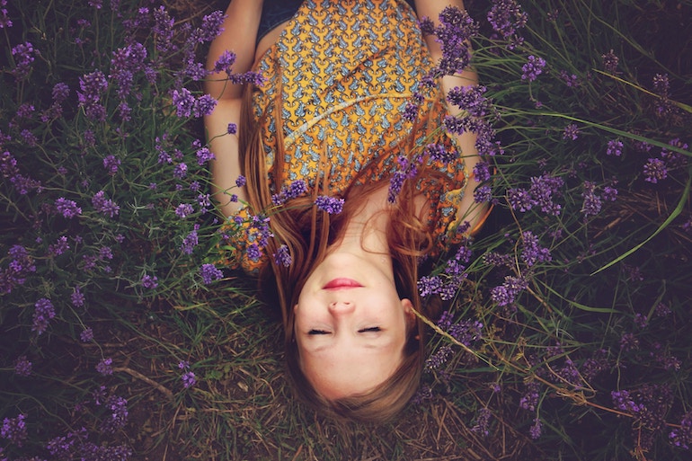 junge Frau liegt auf einer Blumenwiese innere Ruhe innerer Frieden