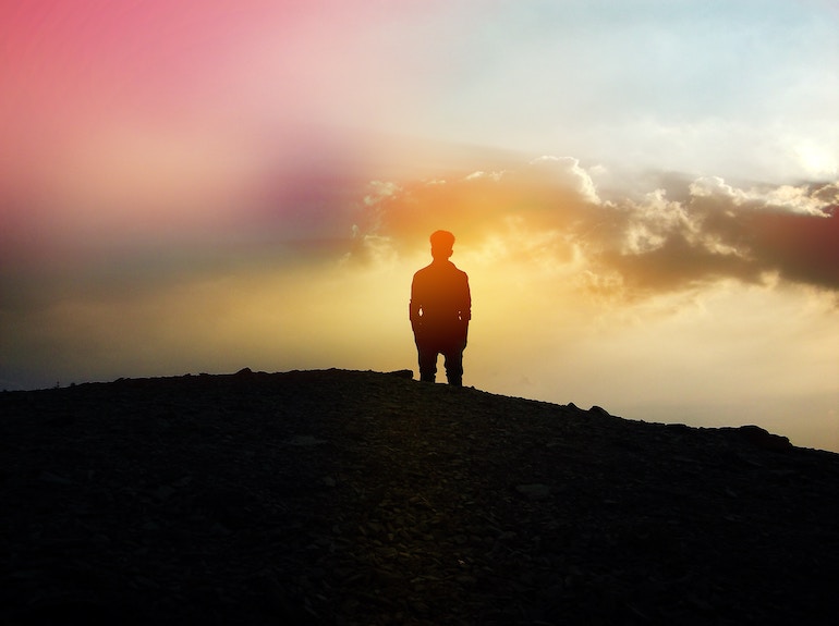 junger Mann steht alleine auf einem Berg - Sonnenuntergang Einsamkeit