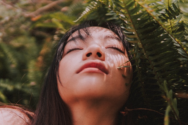 junge Frau mit geschlossenen Augen bei einer Pflanze - seelenverwandt