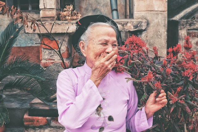 ältere glückliche asiatische Frau mit Blumen in der Hand