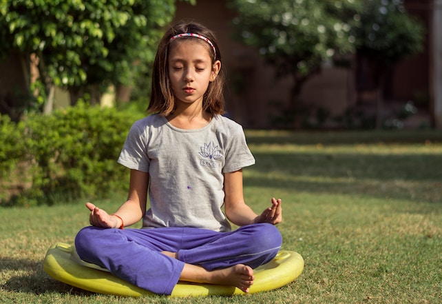 kleines Mädchen meditiert auf der Wiese - Achtsamkeitsübungen