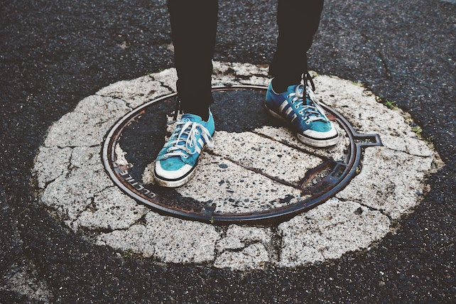 Blaue Sneaker stehen auf dem Asphalt - Selbstfindung - Wer bin ich?