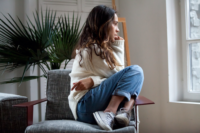 junge Frau sitzt auf einem Sessel und schaut aus dem Fenster - sich selbst verzeihen