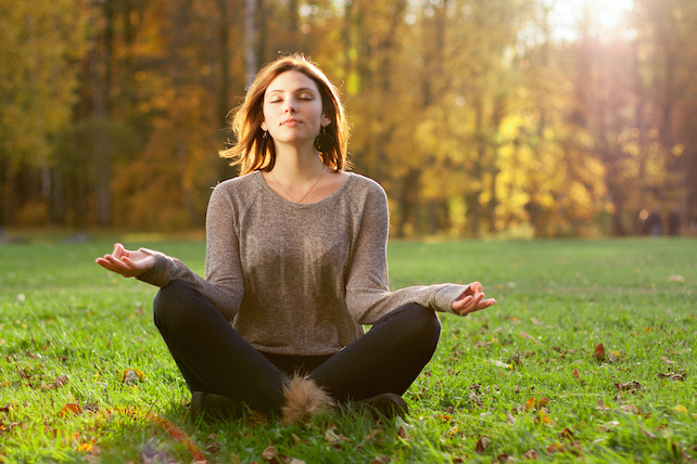 junge Frau meditiert auf der Wiese