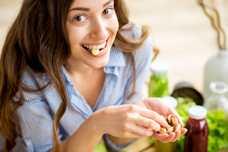 junge Frau isst Cashewnüsse - Nervennahrung