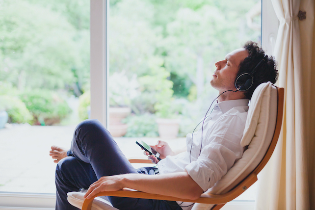 Mann sitzt und hört Musik - Entspannungstechniken