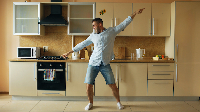 junger Mann tanzt in der Küche und freut sich - Gesetz der Resonanz