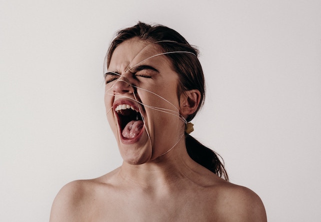 junge Frau schreit - ihr Gesicht ist in Fesseln - junge Frau leidet an Co Abhängigkeit, emotionale Abhängigkeit